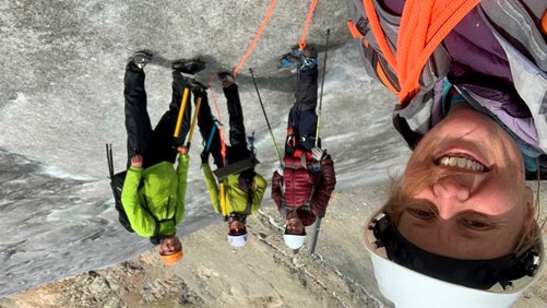 Bethan Davies, left, with colleagues, wearing hard hats and ropes, standing on a glacier