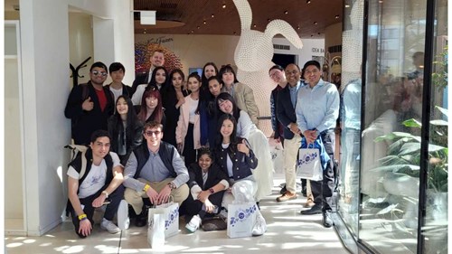 A group of Postgraduate students standing in a foyer posing and smiling towards the camera