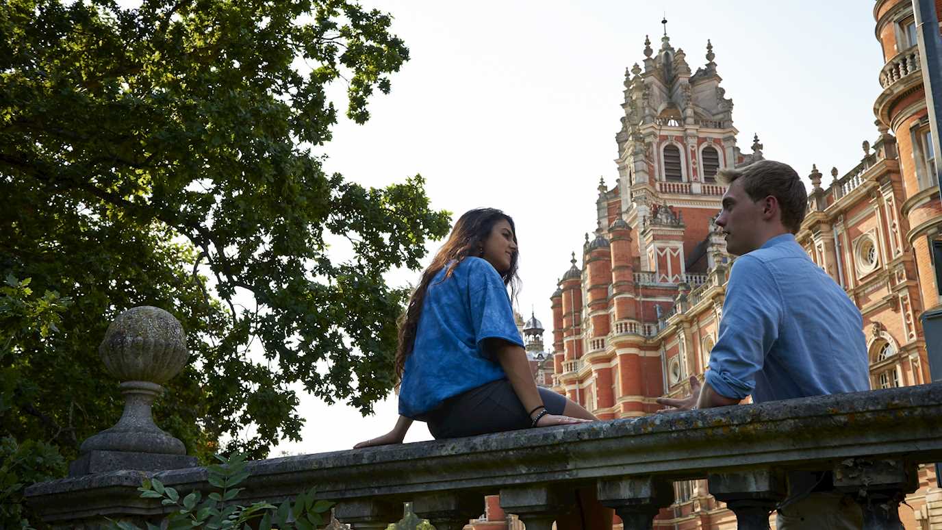 Postgraduate students sitting on wall with Founder's South in background